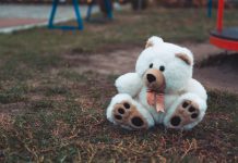 A white teddy bear has been abandoned at a playground.