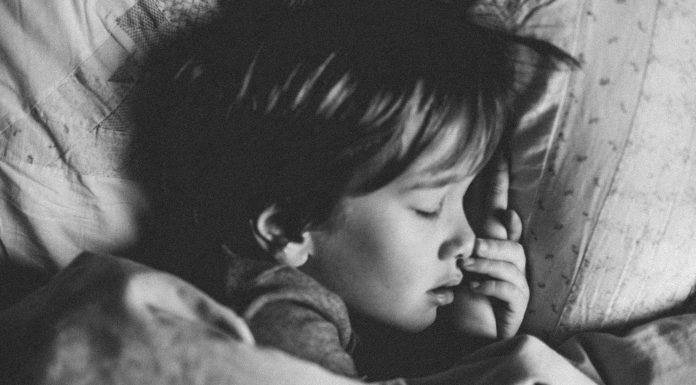 A black and white photo of a child sleeping in their bed.