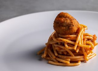 A small twirl of spaghetti with a meatball on top.