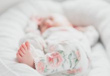 A blurred photo in which a newborn's foot is in focus.