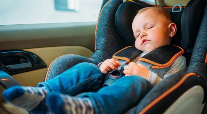 A toddler sleeps in a carseat.