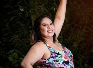 Cecilia Altamirano stands in front of a tree, smiling and lifting her arm up to pose for the camera.