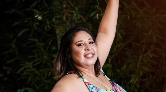 Cecilia Altamirano stands in front of a tree, smiling and lifting her arm up to pose for the camera.