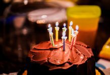 A chocolate birthday cake with 8 lit candles.